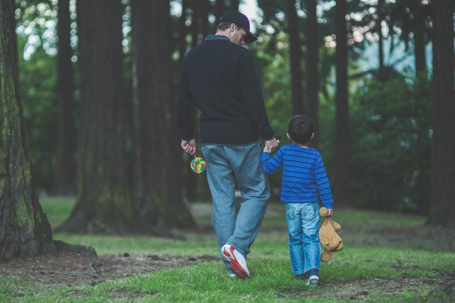 Father and child walking through a wooded park